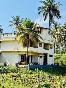 a building with palm trees in front of it at Almond Villa in Kappil
