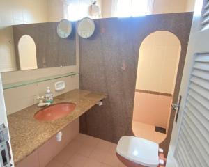 a bathroom with a sink and a toilet and mirrors at FRENTE MAR CASTELHANOS Casa Recanto Azul 7 Suítes Lazer Completo e Conforto recém reformada para Até 25 Pessoas Ideal para reunir Famílias e Amigos in Anchieta