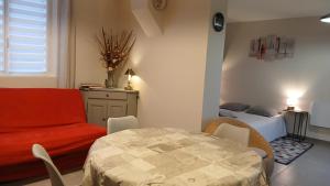 a living room with a red couch and a table at Gite Haute Epine "Ma Vie Là " Studio avec cuisine in Haute-Épine