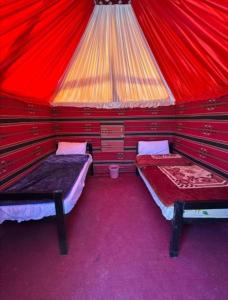 a room with two beds in a red tent at Wadi Rum safari camp in Wadi Rum