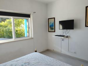 a white bedroom with a bed and a window at Monte Sol Nascente in Grândola