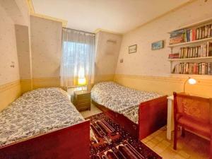 a bedroom with two beds and a book shelf at La Clé de Marc in Le Vésinet +1 photo