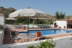 - une table avec un parasol à côté de la piscine dans l'établissement Casa Cruz Resort Eco Naturalists, à Villanueva de Tapia