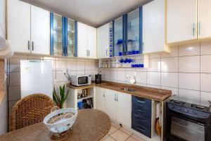 a kitchen with white cabinets and a table and a refrigerator at Apartamento com Varanda, Churrasqueira e Vista Mar in Meia Praia