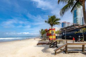 a beach with benches and palm trees and the ocean at Apartamento com Varanda, Churrasqueira e Vista Mar in Meia Praia