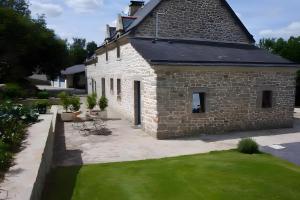 a stone house with a green lawn in front of it at A L'abri in Saint-Nolff +14 photos