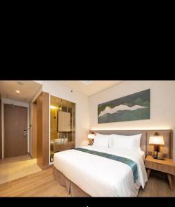 a bedroom with a large white bed and a bathroom at Marianna Resort & Convention Tuktuk - Samosir, Marclan Collection in Ambarita