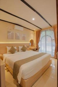 a bedroom with a large white bed and a window at Marianna Resort & Convention Tuktuk - Samosir, Marclan Collection in Ambarita