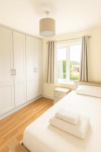a white bedroom with white cabinets and a large window at 3 Bed Spacious House in Castletroy, Limerick 