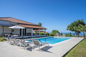 een villa met een zwembad en stoelen bij Villa Serenità - with private pool and ocean view in Ricadi