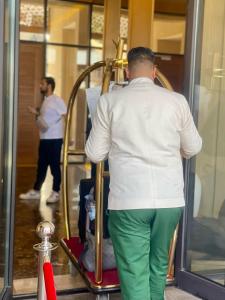 マラケシュにあるM Résidence Marrakech Luxury Serviced Apartmentsの緑のズボンと白いシャツを着た男性がドアを覗いている