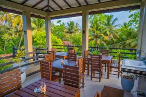 a restaurant with tables and chairs on a balcony at Downsouth Cabanas in Habaraduwa