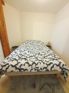 ein Bett mit einer schwarz-weißen Decke drauf in der Unterkunft Appartement Saint Martin in Ussel