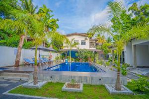 a swimming pool with palm trees in front of a house at Downsouth Cabanas in Habaraduwa