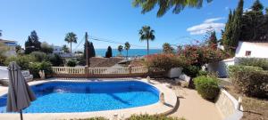 een zwembad in een tuin met een hek en de oceaan bij Appartement Estaño in La Caleta