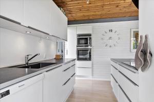 Norsmindeにある30144-Kysing-Naes-Odder-Naesvej-44の白いキャビネットと壁掛け時計付きのキッチン