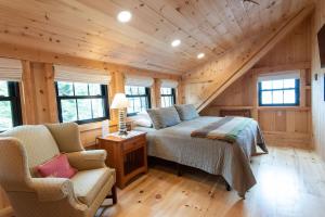 Un dormitorio en una cabaña de madera con una cama y dos sillas. en Oceanview Barnhouse Retreat with Hot Tub, en Steuben