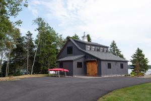un gran granero gris con techo rojo en Oceanview Barnhouse Retreat with Hot Tub, en Steuben