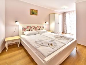 a bedroom with a large white bed with towels on it at Sirena Palace Family Hotel in Obzor