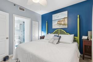 a bedroom with blue walls and a white bed at Beach Club unit 502C- Catalina in Gulf Highlands