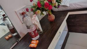 a table with a bottle and a vase with flowers at Stay Classy Inn in Mahabaleshwar
