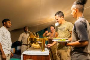 a group of people standing around a table with a plate of food at Mutsviri Game Lodge in Victoria Falls
