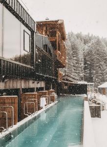een zwembad bedekt met sneeuw naast een gebouw bij Jufenalm BOHO & Wellnesshotel in Maria Alm am Steinernen Meer