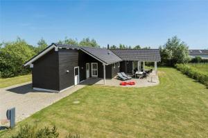 een klein zwart gebouw met een terras en een tuin bij 30460-Odder-Strandvaenget-16 in Odder
