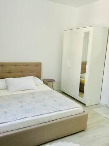 a white bedroom with a bed and a mirror at Bella Home2 in Roşu