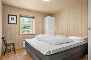 a bed in a room with a chair and a window at 30459-Odder-Solskraenten-2 in Odder