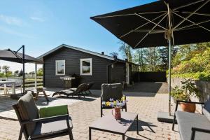 a patio with chairs and an umbrella and a house at 30459-Odder-Solskraenten-2 in Odder