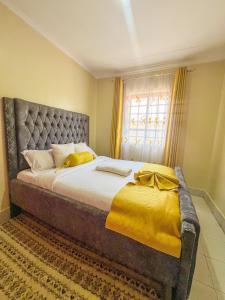 a bedroom with a large bed with yellow sheets and a window at Naka homes in Lanet