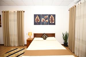 a bedroom with a bed with white sheets and curtains at Ideal Residence in Matara