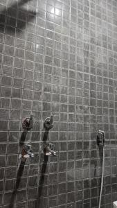 een betegelde douche met twee kranen aan de muur bij Hotel Glass Castle Near Yashobhoomi in New Delhi