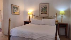 een slaapkamer met een bed met witte lakens en 2 lampen bij Stonehurst Guest House in Kaapstad