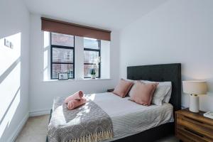 een slaapkamer met een bed met roze kussens en een raam bij Modern Leeds Central Stay -2 min walk from station in Leeds