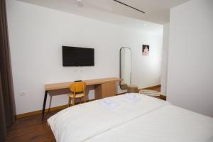 a bedroom with a bed and a desk with a television at Calma Experience in Korçë