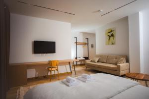 a room with a bed and a couch and a television at Calma Experience in Korçë