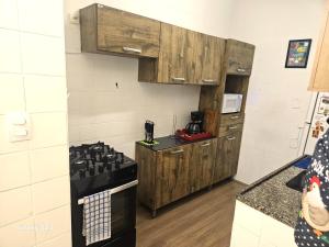 a kitchen with wooden cabinets and a stove top oven at Edificio ALONE com terraço na quadra da praia, espaçoso e silencioso in Rio de Janeiro