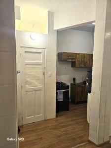a kitchen with a white door and a kitchen counter at Edificio ALONE com terraço na quadra da praia, espaçoso e silencioso in Rio de Janeiro