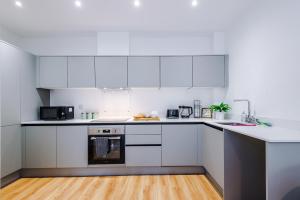 een witte keuken met witte apparatuur en een houten vloer bij Modern Leeds Central Stay -2 min walk from station in Leeds +22 foto's