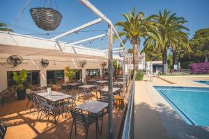 a restaurant with tables and chairs next to a swimming pool at HolaCamp Sitges Relax in Sitges