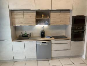 une cuisine avec des armoires blanches, un évier et un lave-vaisselle dans l'établissement Maison confortable avec jardin à Marseille, à Marseille 9 autres photos