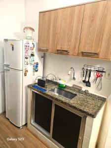 a kitchen with a sink and a refrigerator at Edificio ALONE com terraço na quadra da praia, espaçoso e silencioso in Rio de Janeiro +16 photos