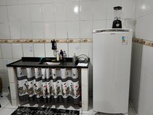 a kitchen with a counter with a sink and a refrigerator at Casa 2 grande perto do pavilhão de Carapina in Serra