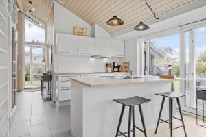 a kitchen with white cabinets and a counter with stools at 30178-Odder-Chr-Christensensvej-9 in Beder
