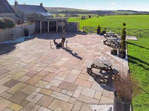 a patio with benches and tables and a dog on it at Red Kite Cottage-Ukc6982 in Consett
