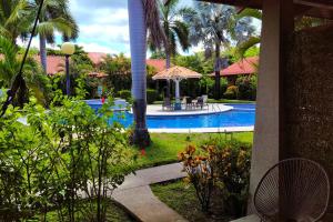 un patio del complejo con piscina y palmeras en Villaggio Claudia 29B, en Potrero