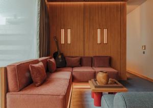 uma sala de estar com um sofá castanho e uma guitarra em The Click Clack Hotel Bogotá em Bogotá