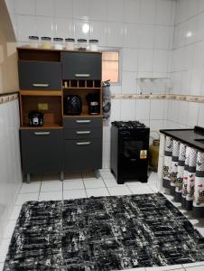 a kitchen with black cabinets and a black rug at Casa 2 grande perto do pavilhão de Carapina in Serra +7 photos
